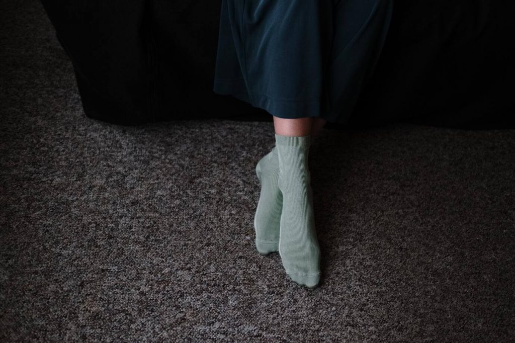 Elegante, mintgrüne Socken am Fuß mit schwarzem Teppich als Hintergrund