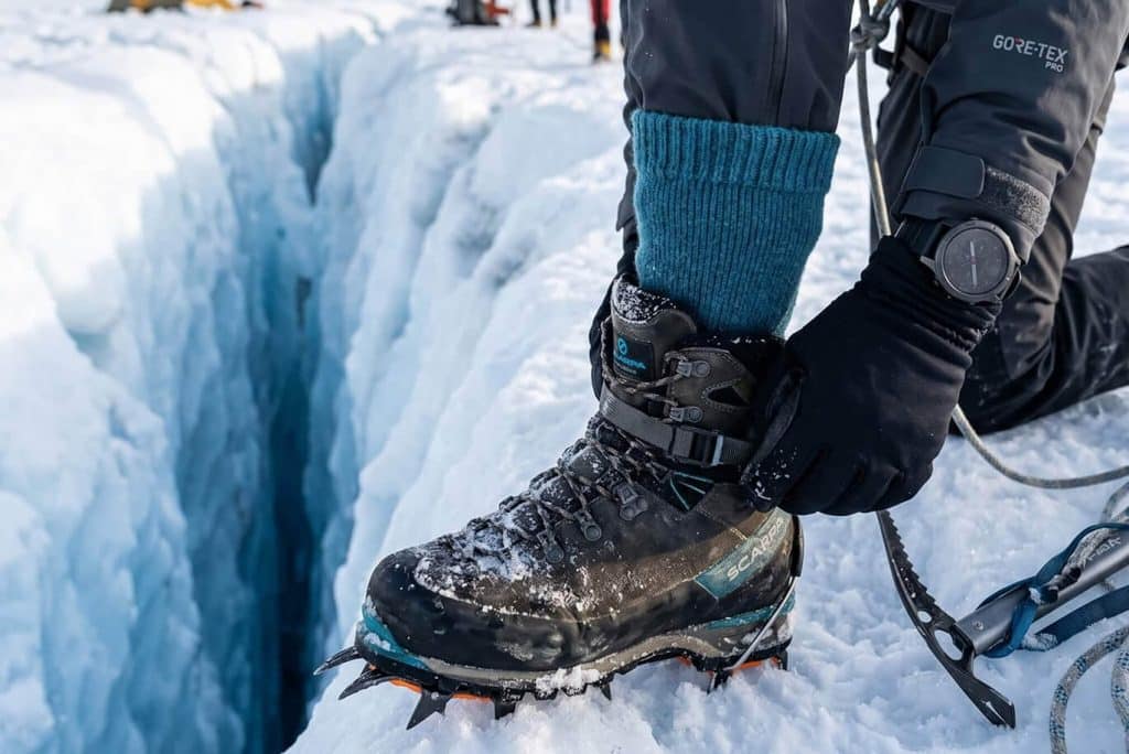 Wärmste Socken aus Alpakawolle getragen in Expeditionsschuhen vor beeindruckender Gletscher Kulisse