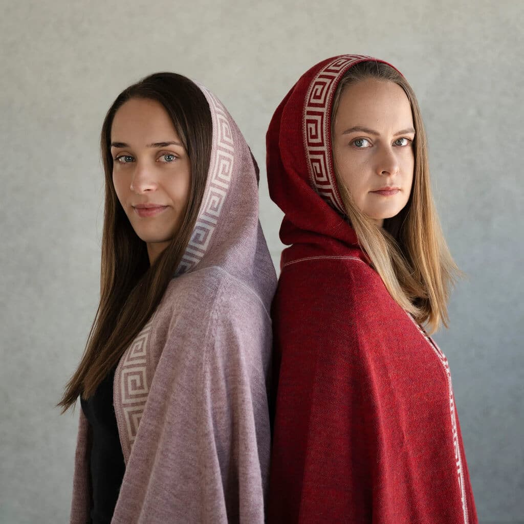 Zwei Frauen tragen den Luz Alpaka Poncho in rosa und rot mit eleganter Musterung