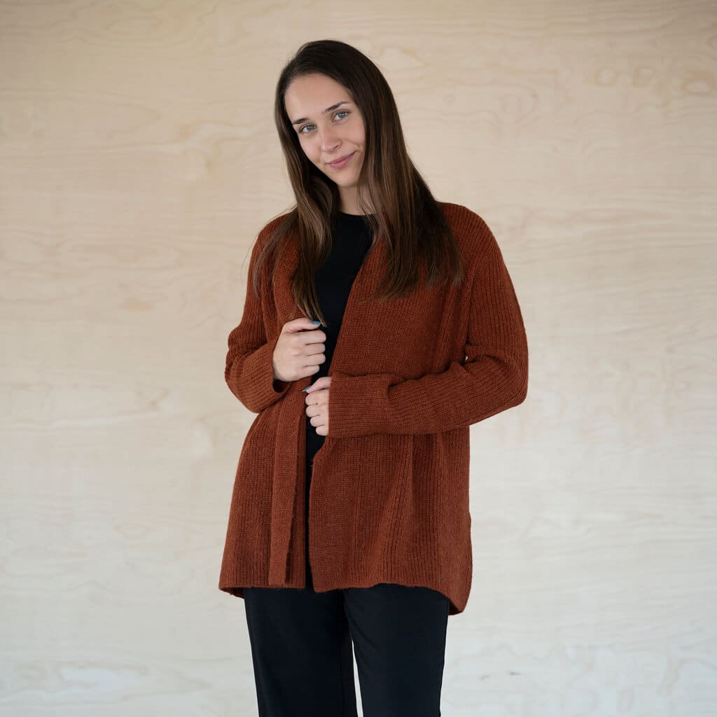 Warmer Alpaka Cardigan Mira in dunkelorange getragen von dunkelhaarigem Model, das frontal in die Kamera blickt