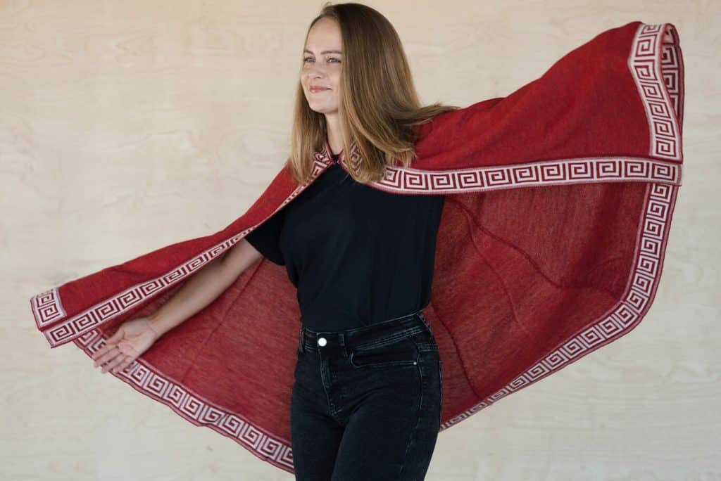 Frau trägt den roten Luz Alpaka Poncho und genießt die Bewegungsfreiheit ihres Ponchos