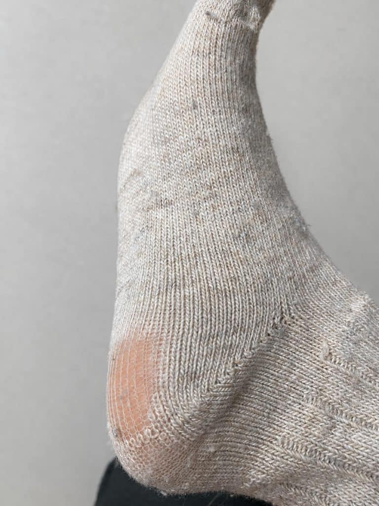 Durchgelaufene Ferse einer klassischen Alpaka Wollsocke in beige