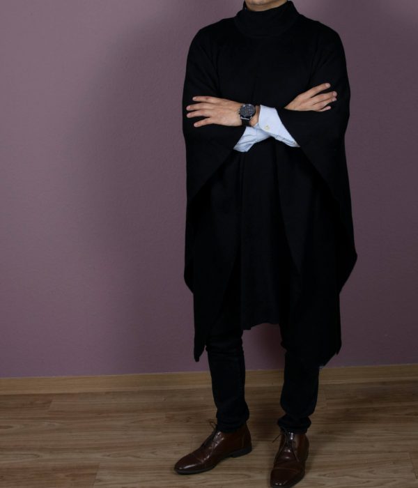 Eleganter Alpaka Poncho für Herren in schwarz von Alpakin, getragen von Mann mit Hemd, der die Arme übereinander legt
