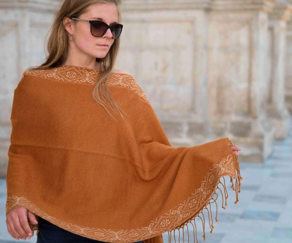 Flor Alpaka Poncho Schal für Damen von Alpakin in kamel getragen von blondem Model mit Sonnenbrille in Peru
